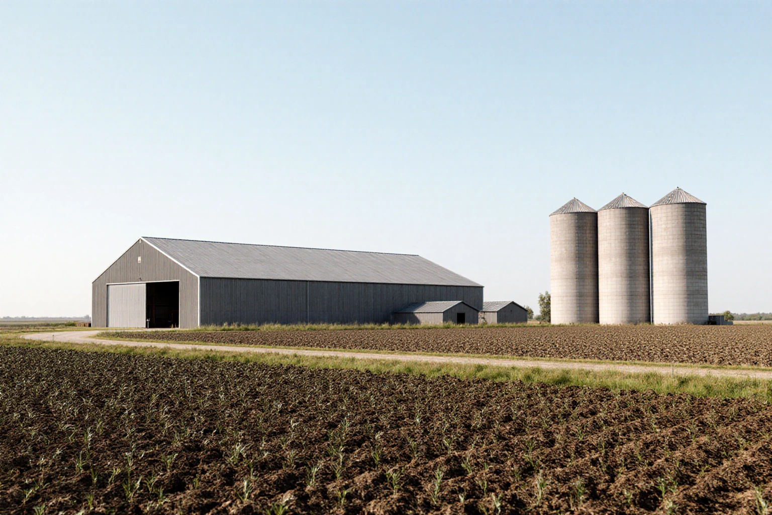Agricultural buildings and grain storage beside cultivated fields